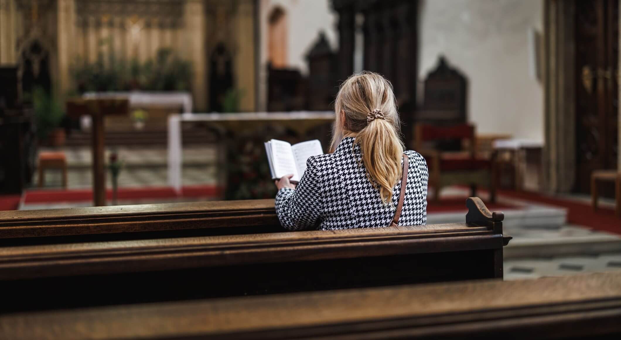 Person reading in church pews.