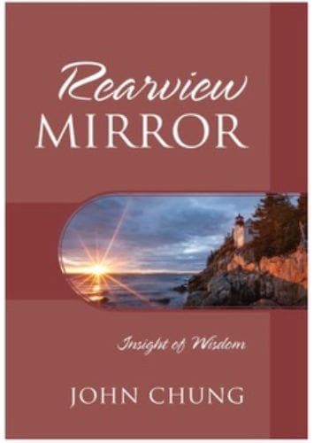 Scenic rearview mirror reflecting a coastal lighthouse at sunset.