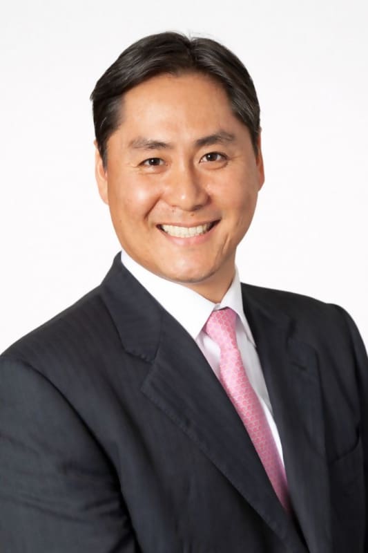Smiling man in a suit with pink tie.