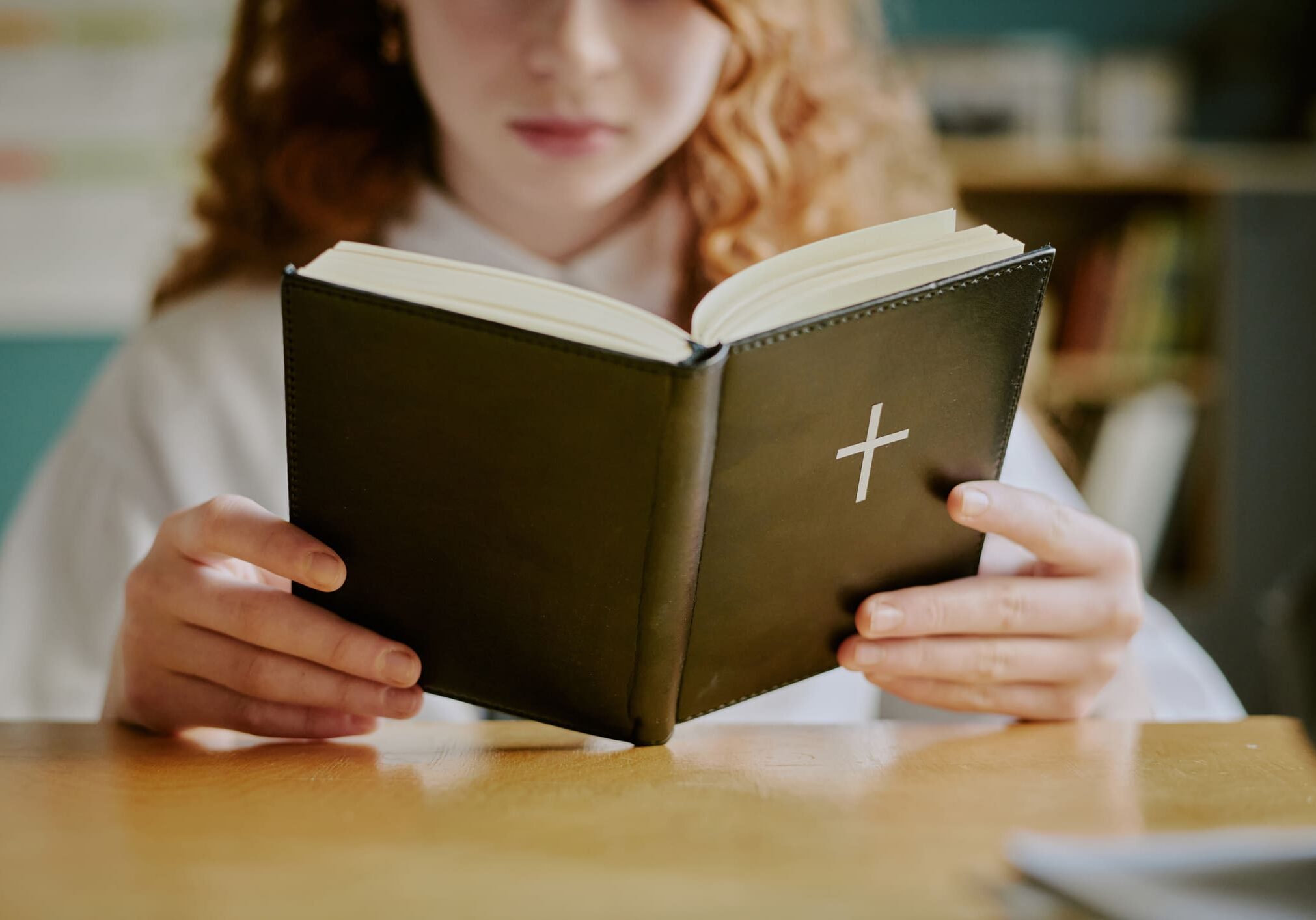 Person reading a book with a cross.